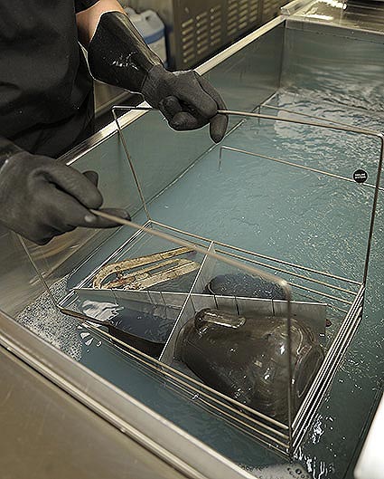 glassware covered in soot being submerged into an ultrasonic bath